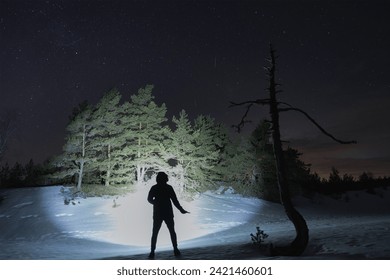 Photo with low lighting, silhouette of a man with a knife in his hand in a winter forest. High quality photo
