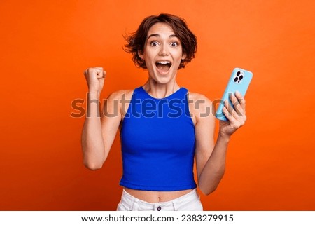 Photo of lucky impressed lady wear blue singlet rising fist online discount shopping modern device isolated orange color background
