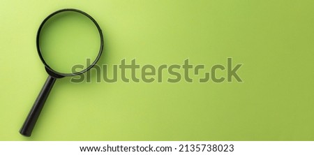 Photo of magnifying glass on left side over green pastel background with copyspace for put your text or logo.,Flat lay top view mock-up item concept.