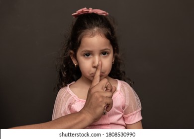 Photo of male hand making silence sign on little girl's mouth. Concept of infant sexual abuse and violence. 