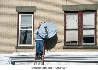 photo of a male on a ladder installing a tv dish