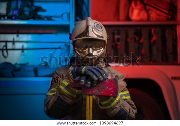 Photo of man fireman in helmet and helmet with pick\
on background of fire\
truck