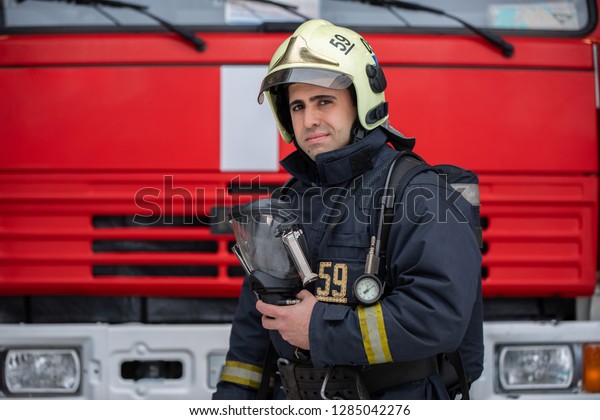 Photo\
of man fireman with mask in hands near fire\
truck