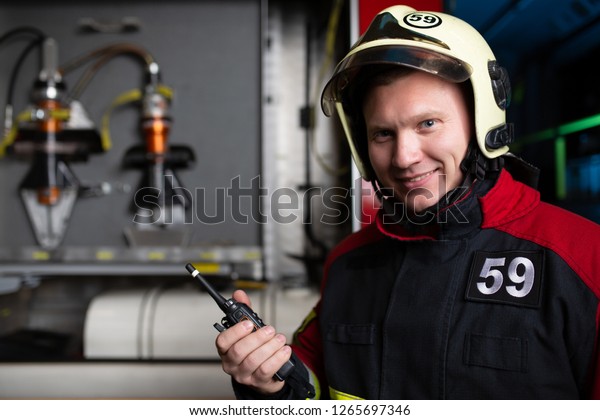 Photo of man fireman with walkie-talkie in hands on\
background of fire truck