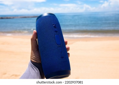 Photo Of A Man Hand Holding A Portable Speaker At The Beach 