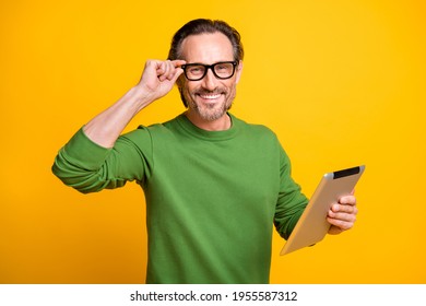 Photo of man hold tablet toothy shiny smile look camera wear specs green sweater isolated yellow color background