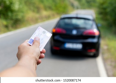 Photo of a man holding a new driving license in his hand outdoor