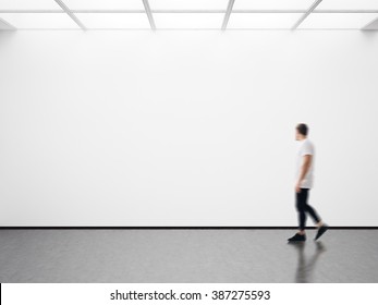 Photo of man in modern gallery looking at the empty canvas. Blank mockup, motion blur 