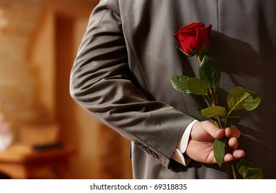 Photo Of Man In Suit Holding A Red Rose Behind His Back