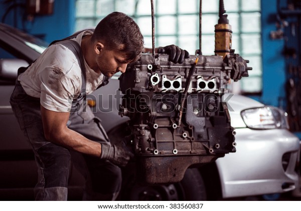 Photo of man in\
uniform repairing broken\
engine