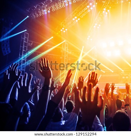Photo of many people enjoying rock concert, crowd with raised up hands dancing in nightclub, audience applauding to musician band, night entertainment, music festival, happy youth, luxury party