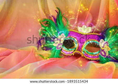 Photo of Mardi Gras and Purim mask over colorful chiffon background