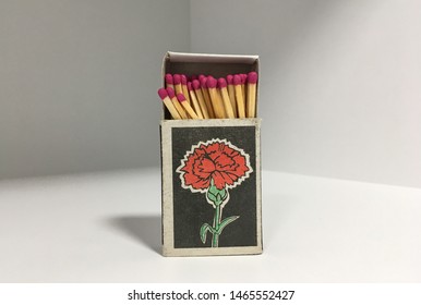 
Photo of matches in a matchbox with a carnation flower drawn on a light background with shadows. Matches with a sulfur head of a red shade.  The box is open - Powered by Shutterstock