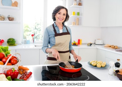 Photo of mature brunette nice lady cook meat wear apron jeans shirt at kitchen alone