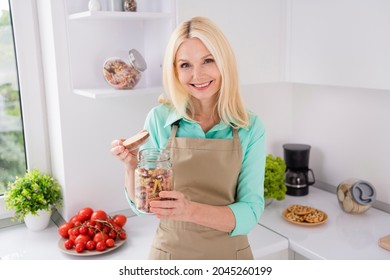Photo of mature cheerful woman happy positive smile open jar recipe cooking dish lunch ingredient indoors
