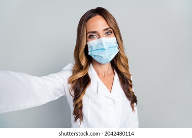 Photo Of Mature Happy Woman Hold Hand Camera Selfie Face Doctor Wear Mask Isolated On Grey Color Background