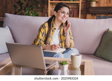 Photo of mature joyful woman look hold hand phone notebook talk smile work enjoy inside house home flat