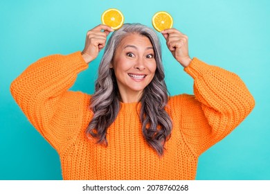 Photo Of Mature Lovely Woman Have Fun Hold Orange Pieces Like Pet Ears Isolated Over Teal Color Background