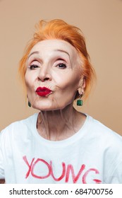 Photo Of Mature Redhead Fashion Woman Sitting Isolated At Studio Posing. Looking Camera Blowing Kisses.