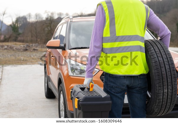 Photo of a mechanic dressed in\
high-visibility vest and ready to help, rear view. Professional\
emergency road service. RoadSide\
Assistance.