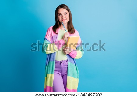 Photo of minded beautiful brown haired girl look empty space hold notebook pen chin creative project isolated on blue color background