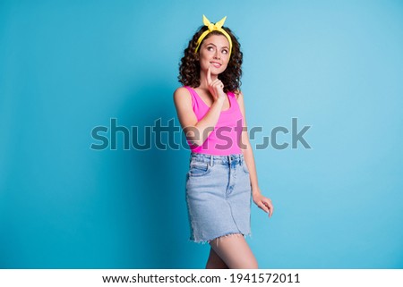 Photo of minded girl look empty space hold finger chin bite lip wear pink singlet yellow headband isolated on blue color background