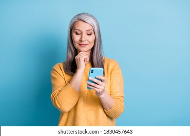 Photo of minded old woman use smartphone think thoughts decide texting typing social media chatting wear style stylish jumper isolated over blue color background - Powered by Shutterstock