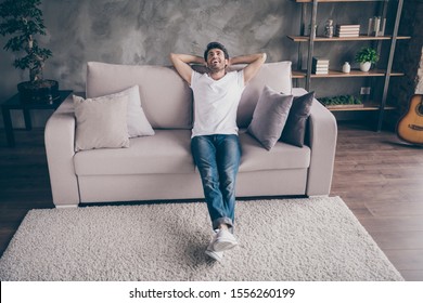 Photo Of Mixed Race Arabian Guy Sitting Cozy Sofa Holding Hands Behind Head Relaxing Homey Weekend Mood Looking Dreamy Up Wear Casual Outfit Flat Loft Living Room Indoors