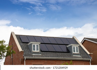 Photo of a modern British house in the UK with electrical solar panels on the roof on a bright sunny day with clouds in  the sky