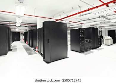 A photo of a modern server room with rows of black server racks and a visible fire suppression system with red pipes running along the ceiling. The room has a clean, professional appearance with white - Powered by Shutterstock