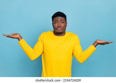 Photo Of Multinational Guy Dude Dont Know Shrug Shoulders Hold Both Arms Novelty Wear Yellow Shirt Isolated Blue Color Background