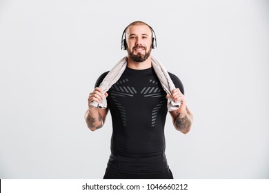 Photo Of Muscular Man Listening To Music Via Headphones And Holding Towel On Neck After Workout Isolated Over White Background