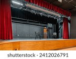 Photo of a new school stage, theater, auditorium, with gray seats, chairs.	