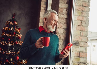 Photo of nice aged man hold coffee smart phone look window wear sweater christmas festive holiday apartment indoors - Powered by Shutterstock