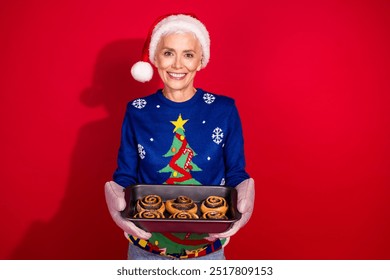 Photo of nice aged woman hold fresh baked buns wear christmas sweater isolated on bright red color background - Powered by Shutterstock