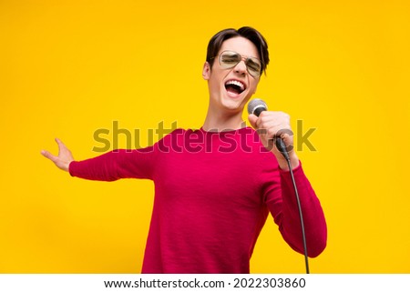 Photo of nice brunet millennial guy sing wear red sweater isolated on yellow color background