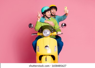 Photo of nice lady guy two people couple best friends drive vintage moped spend vacation make selfies telephone show v-sign wear casual jumper headgear isolated pink color background