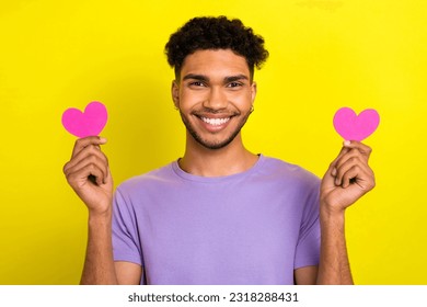 Photo of nice positive friendly man beaming smile arms hold small pink paper hearts isolated on yellow color background - Shutterstock ID 2318288431