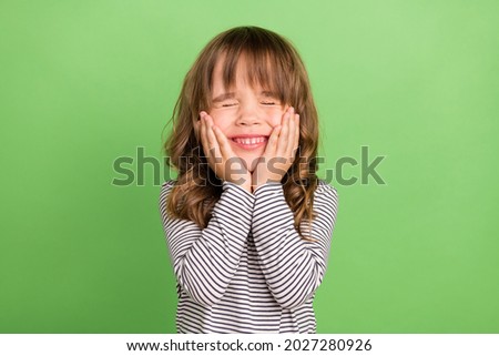 Photo of nice small blond hair girl hands cheeks wear striped shirt isolated on green color backgound