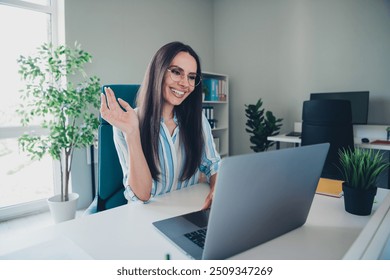 Photo of nice woman video call wave hand hi dressed striped formalwear comfortable light startup office room interior - Powered by Shutterstock