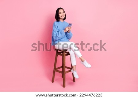 Photo of nice woman wear knit pullover hold smartphone sit on chair facebook twitter instagram whatsapp isolated on pink color background