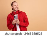 Photo of nice young man phone headphones look empty space wear red shirt isolated on beige color background