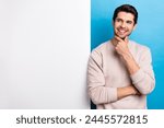 Photo of nice young man think look empty space placard wear beige sweatshirt isolated on blue color background