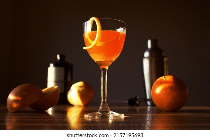 a photo of Nick and Nora orange cocktail with fresh oranges on sunsets background