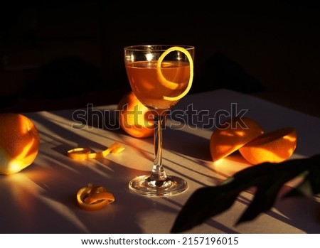 a photo of Nick and Nora orange cocktail with fresh oranges on sunsets background