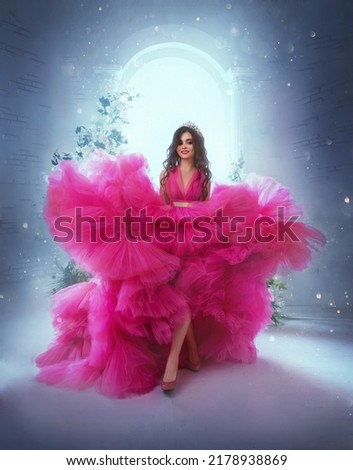photo with noise. Happy fantasy princess in pink ball gown. Queen woman smiling face. Carnival evening puffy lush long neon bright fuchsia color dress. Royal blue room, magical sun light from window