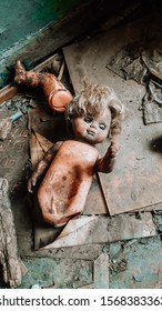 Photo Od The Old Rotten Radioactive Toy Of Doll And Old Notepads Abandoned Among Vegetation And Dirt In The City Of Pripyat, The Chernobyl Disaster, Ukraine, Kiev Region