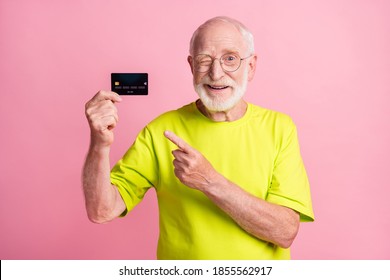 Photo Of Old Cheerful Positive Smiling Man Wear Lime T-shirt Wink Eye Point Finger At Credit Card Isolated On Pink Color Background