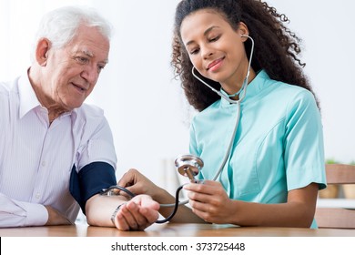 Photo Of Old Male And Nurse Taking Blood Pressure