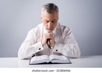 Photo Of Old Man Praying To God With Rosary And Reading Bible